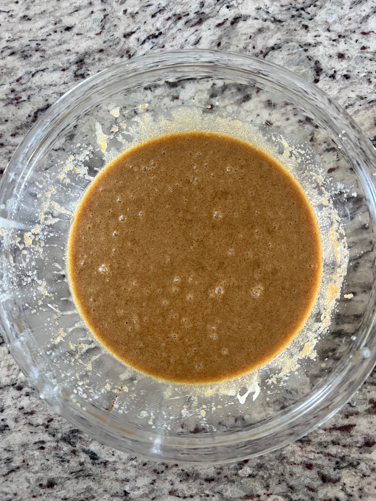 The wet ingredients for the sourdough brown butter caramel apple oatmeal cream pies sit in a glass mixing bowl. 