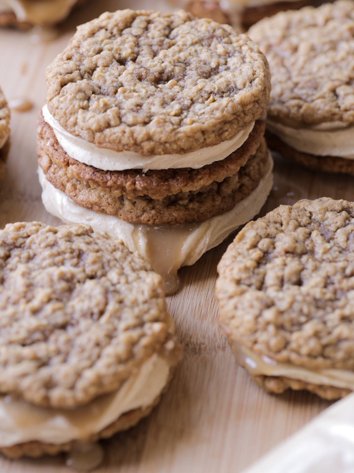 Gooey sourdough brown butter oatmeal cream pies with a brown sugar cream cheese filling and caramel apple sauce is shown stacked and up close.