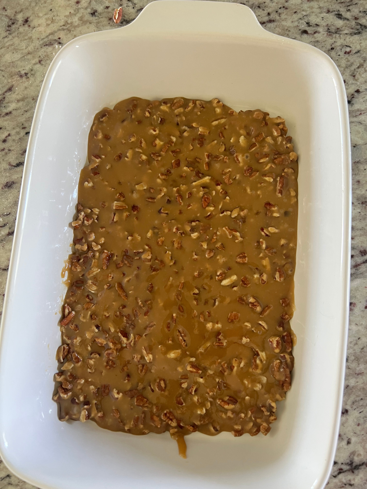 The caramel pecan sauce has been poured into the bottom of the 9x13 baking dish.