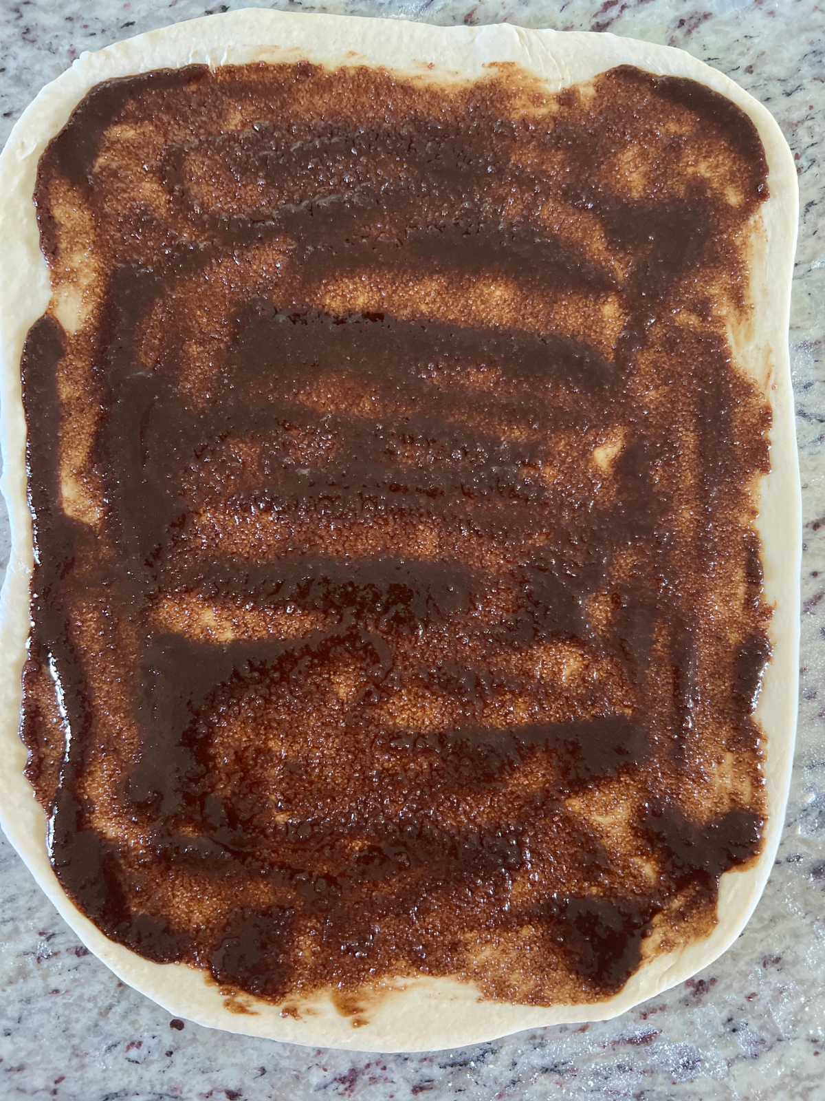 The sourdough sticky bun dough has been rolled out into a rectangle and topped with the cinnamon butter sugar filling.