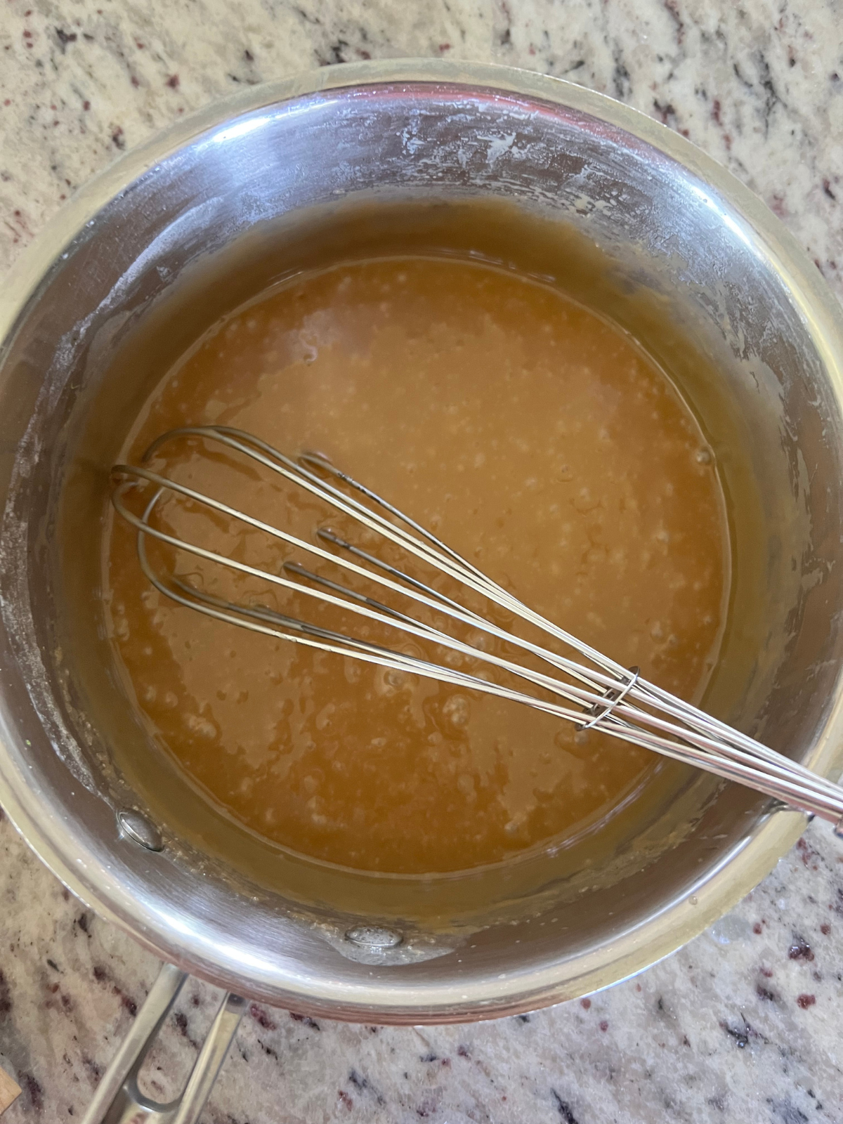 The homemade caramel sauce sits in a medium sized saucepan.