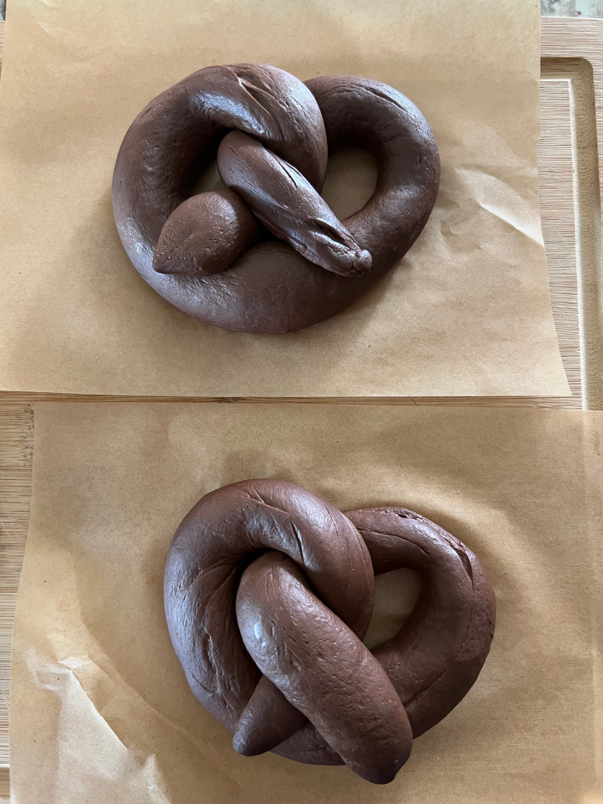 Two sourdough chocolate pretzels are shown after their second rise.