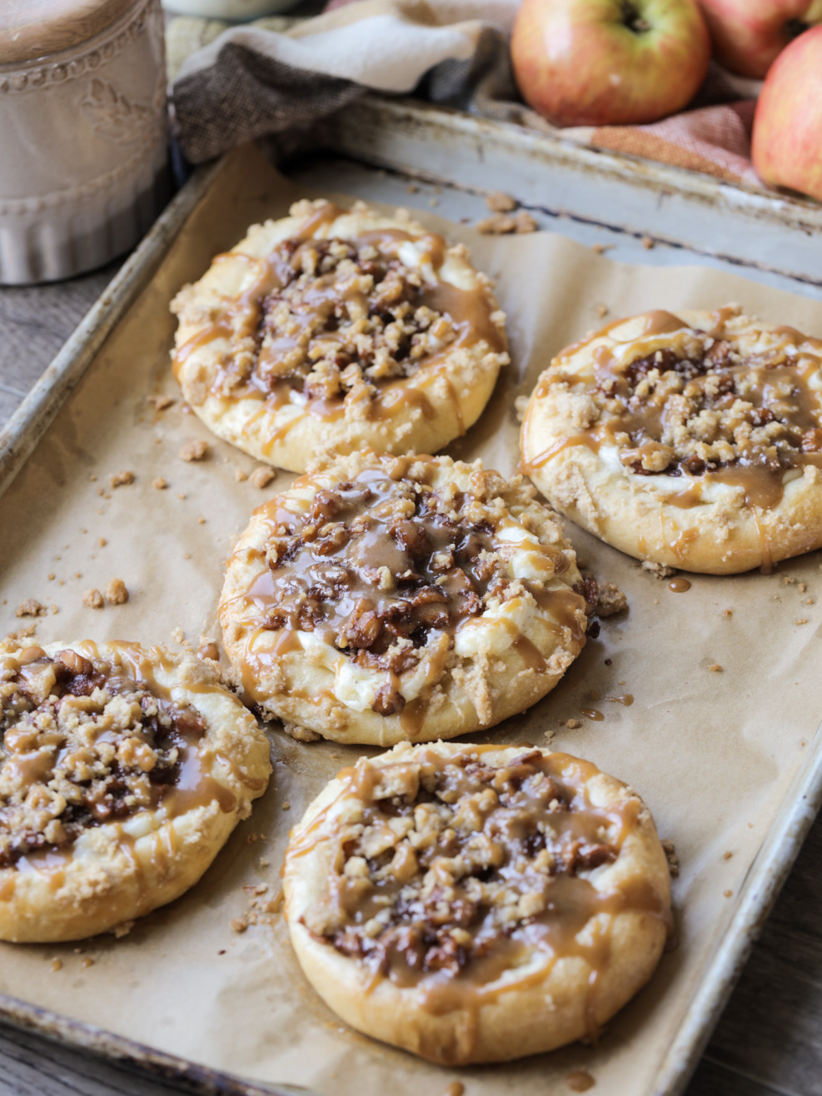 Five sourdough brioche caramel apple cream cheese crumble kolaches sit on a baking sheet. 