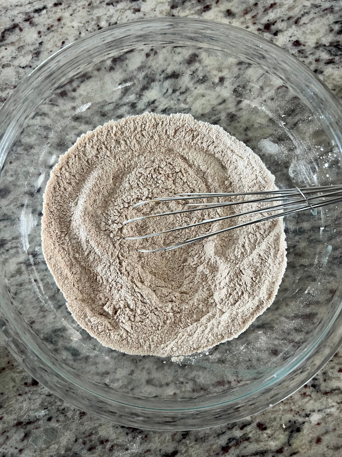 The dry ingredients for the sourdough discard pumpkin coffee cake sit in a glass mixing bowl.