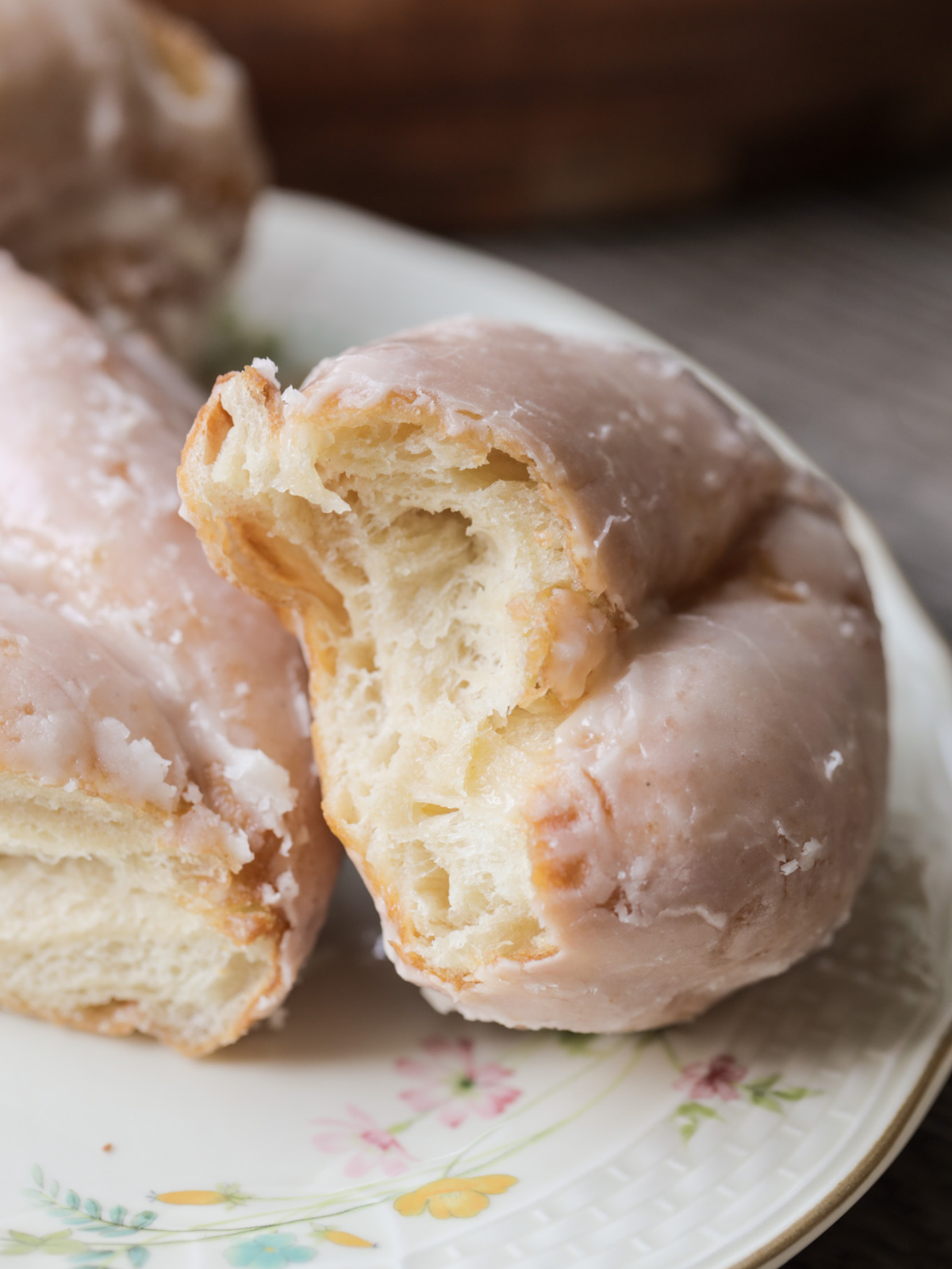 The sourdough brioche maple glazed twist donut is shown with a bite taken out of it--showing the fluffy brioche interior of the donut.