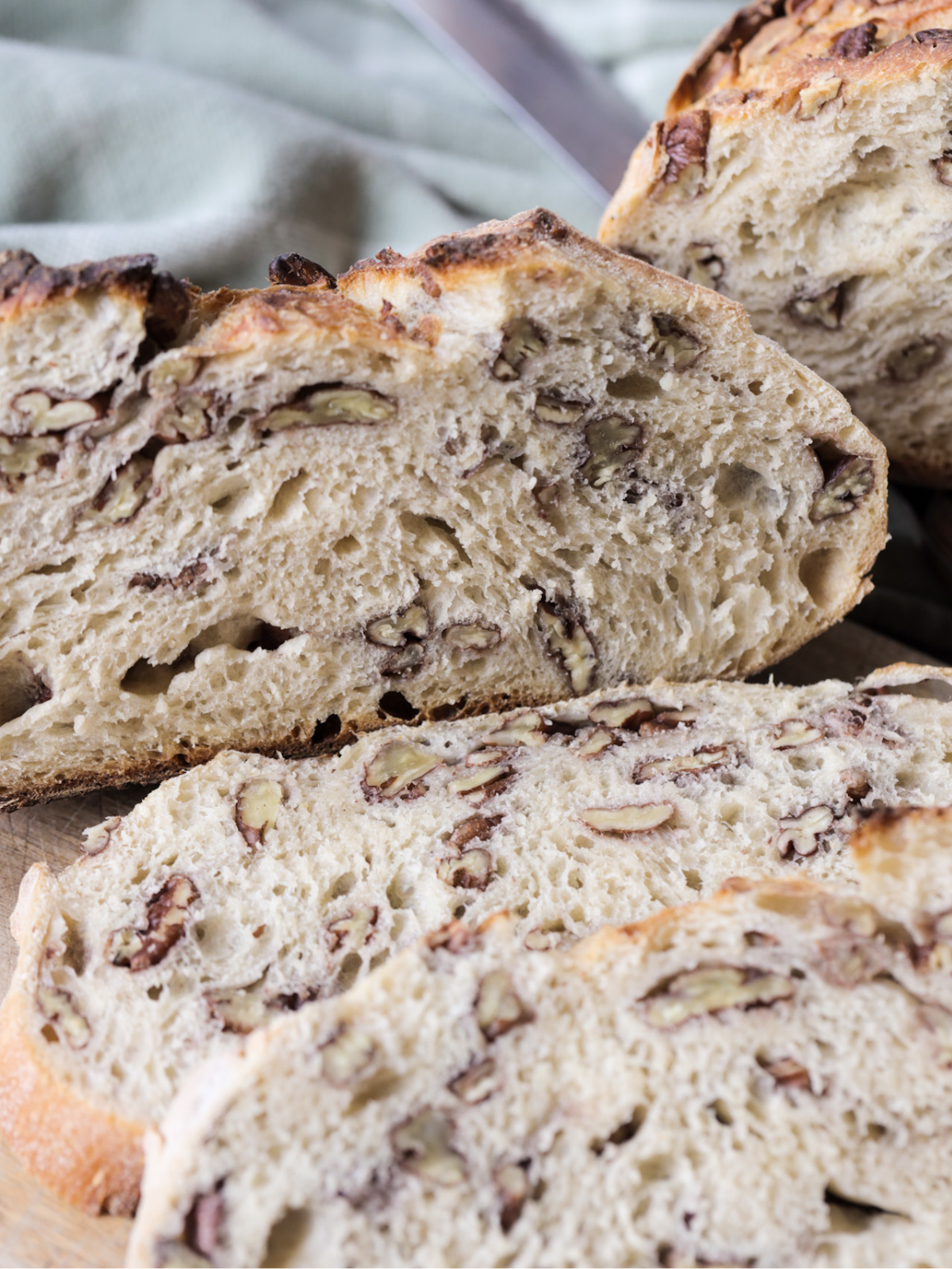 A closeup is shown of the sourdough maple pecan loaf of bread with several pieces in the foreground.