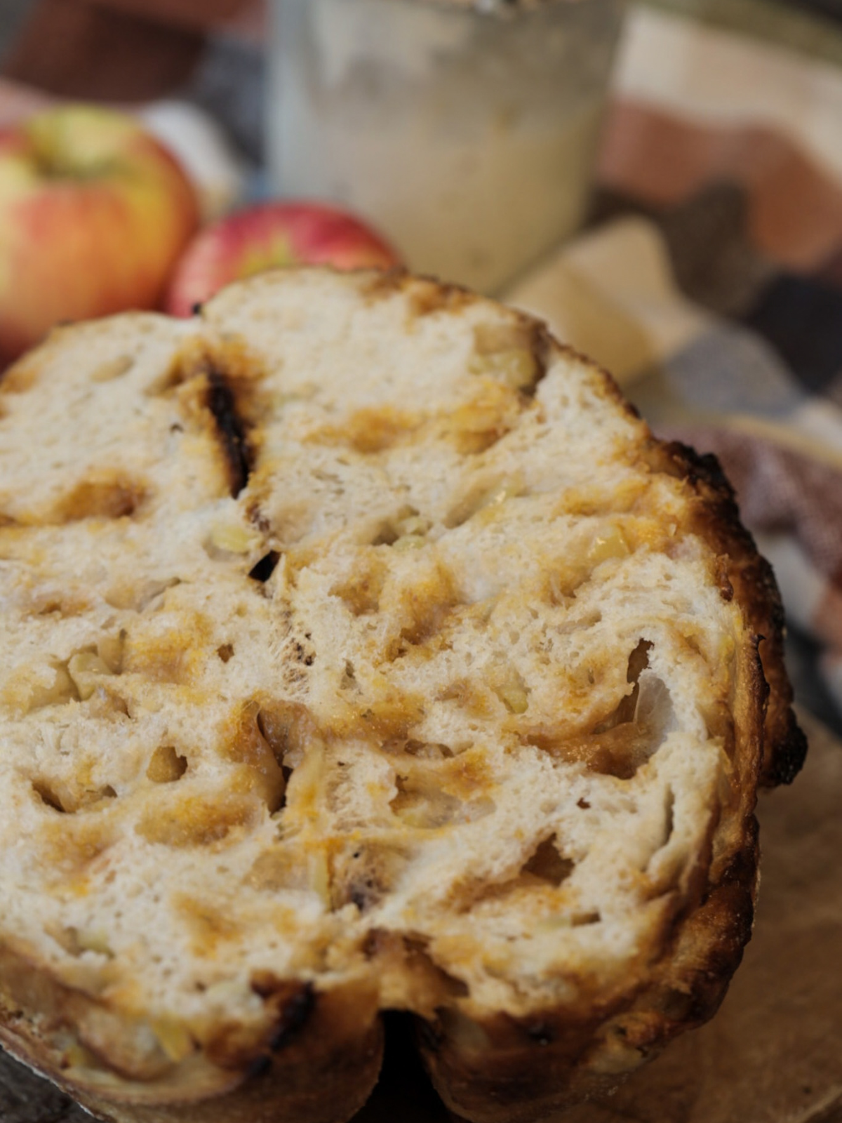 The loaf of apple cider butterscotch sourdough bread is cut in half to reveal the melty butterscotch and chopped apples. 