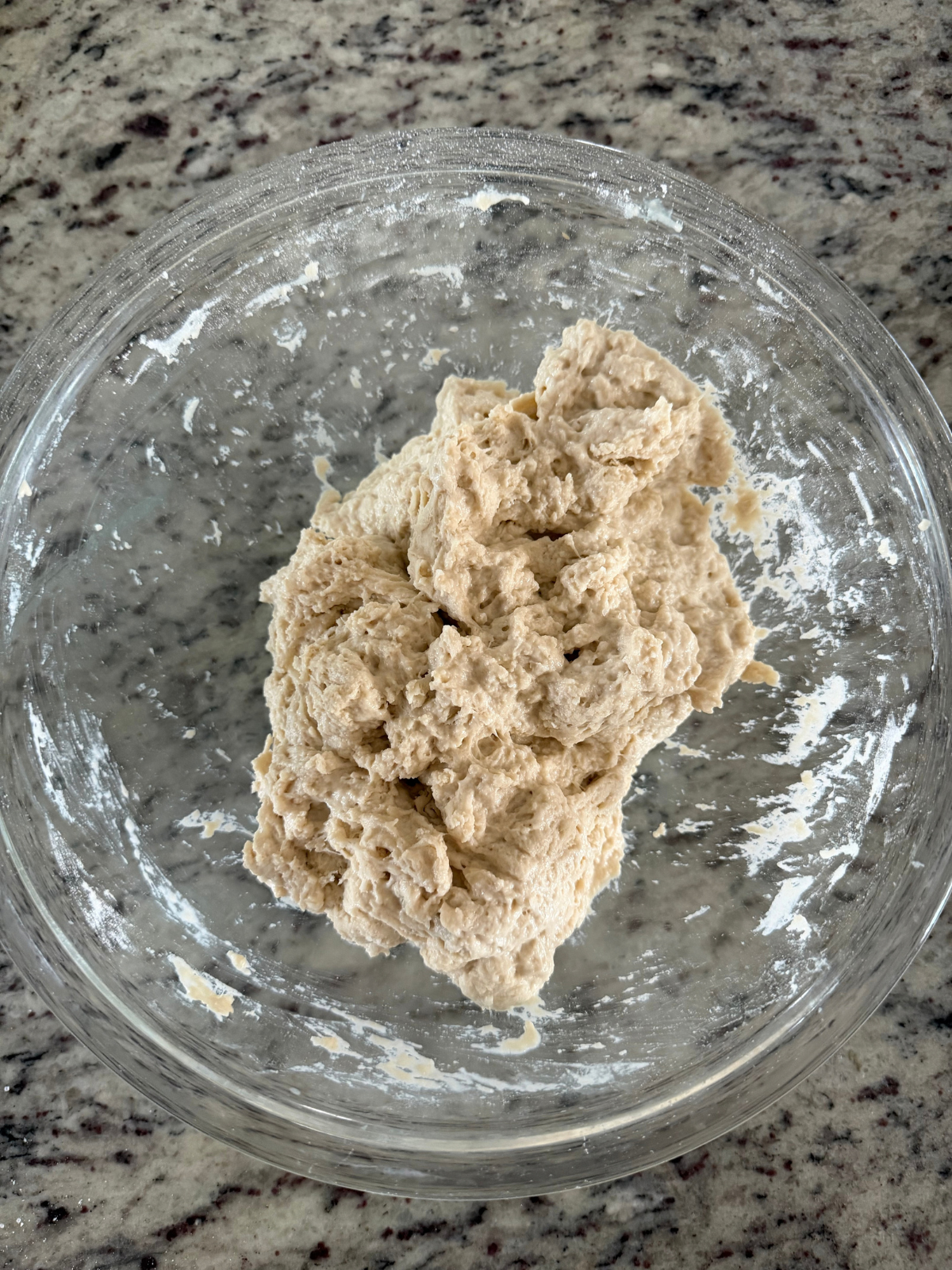 The shaggy dough for the apple cider butterscotch sourdough bread is in the glass mixing bowl. 