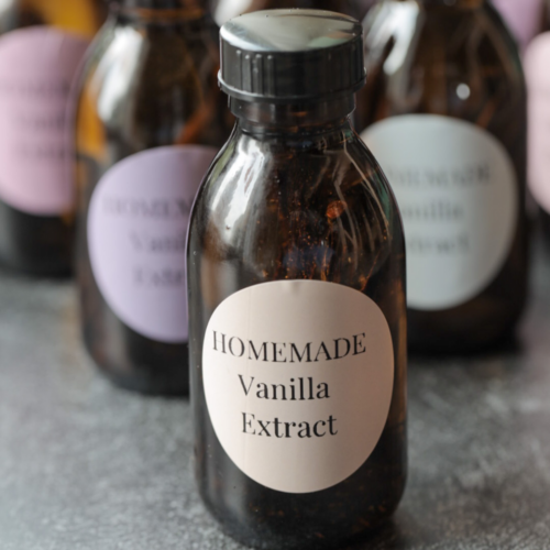 A closeup of homemade vanilla extract with many others in the background.