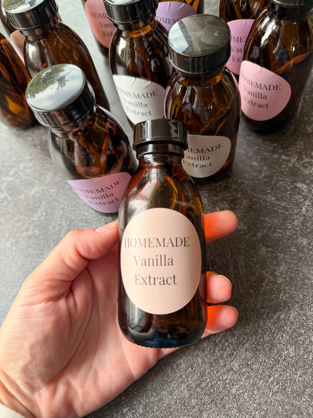 Homemade vanilla extract sits in my hand in an amber glass bottle, which is perfect for preserving the vanilla extract. 