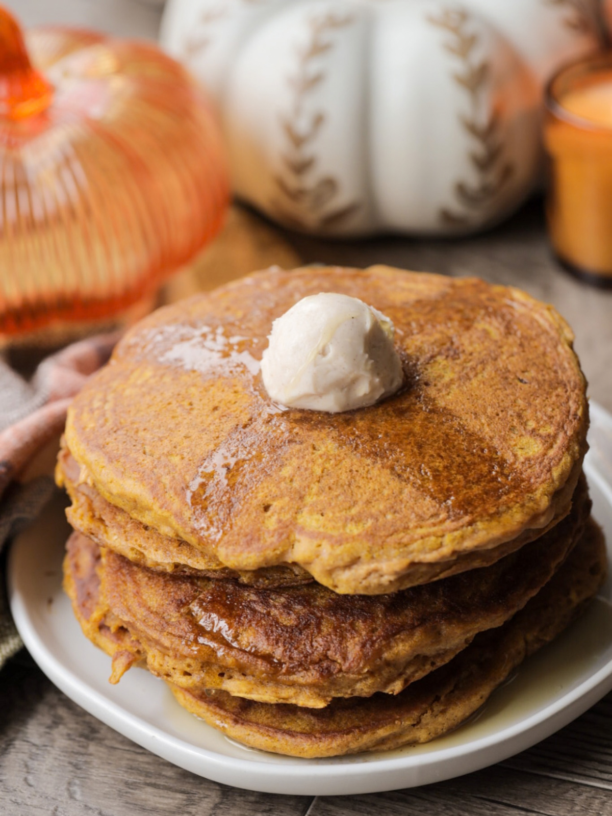 Soft and fluffy sourdough pumpkin pancakes are shown on a plate with cinnamon butter and maple syrup.