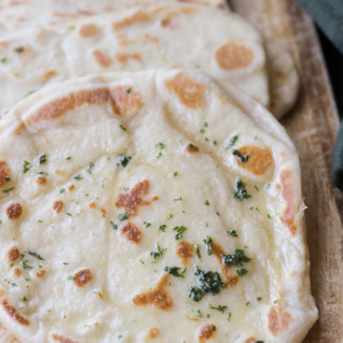 A closeup is shown of this from-scratch sourdough discard naan that is brushed with a cilantro garlic butter.