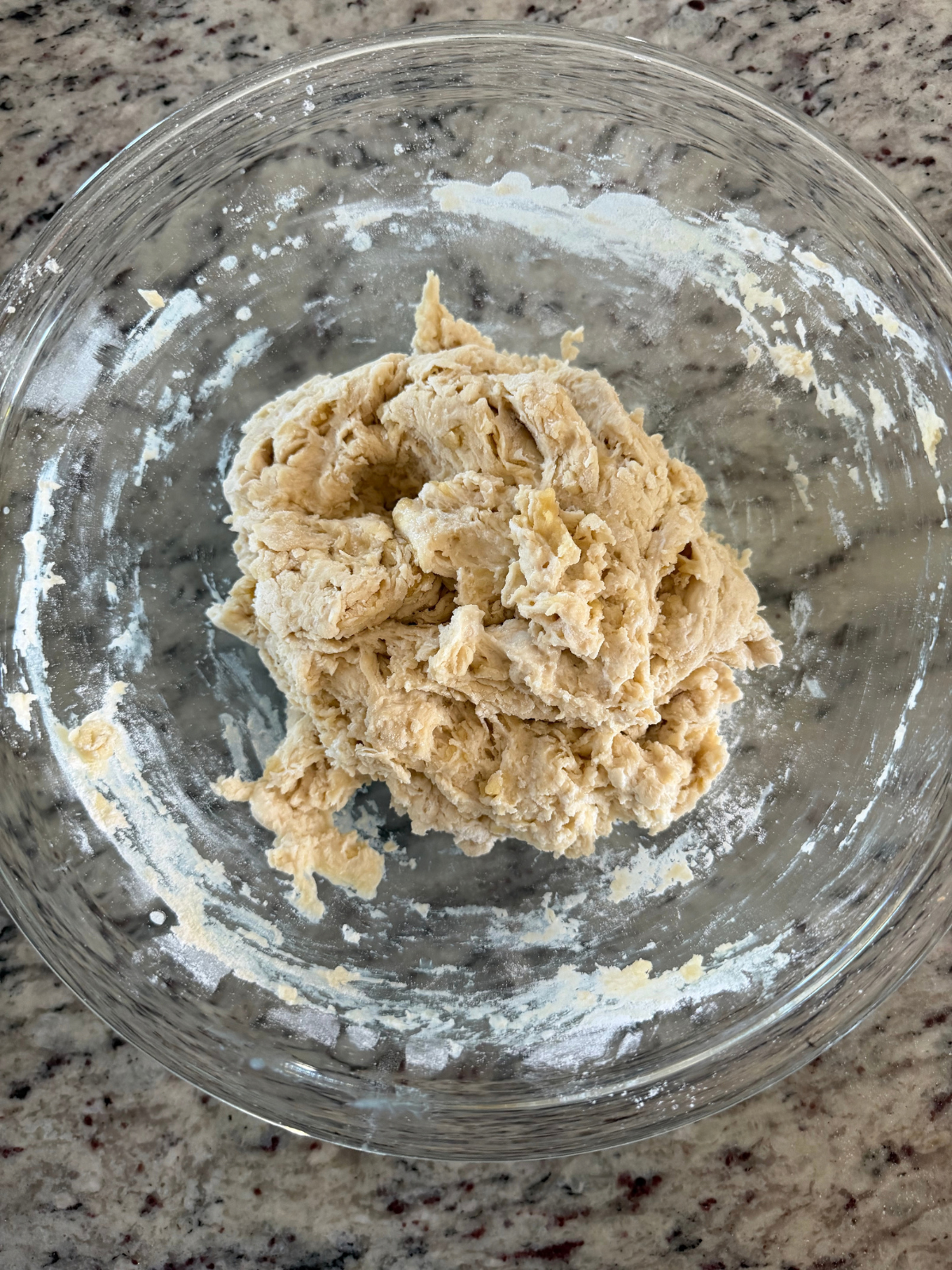 The sourdough discard naan dough sits in a shaggy ball in a mixing bowl.