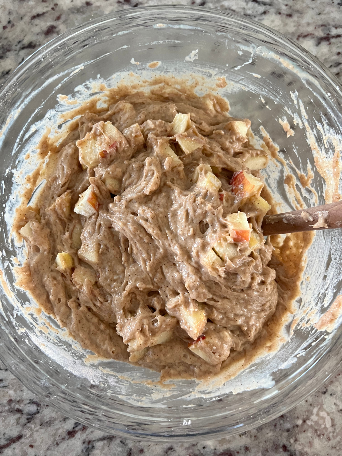 The sourdough discard apple coffee cake batter sits in a glass mixing bowl.