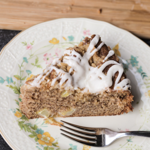A slice of sourdough discard brown butter apple streusel coffee cake sits on a floral plate.