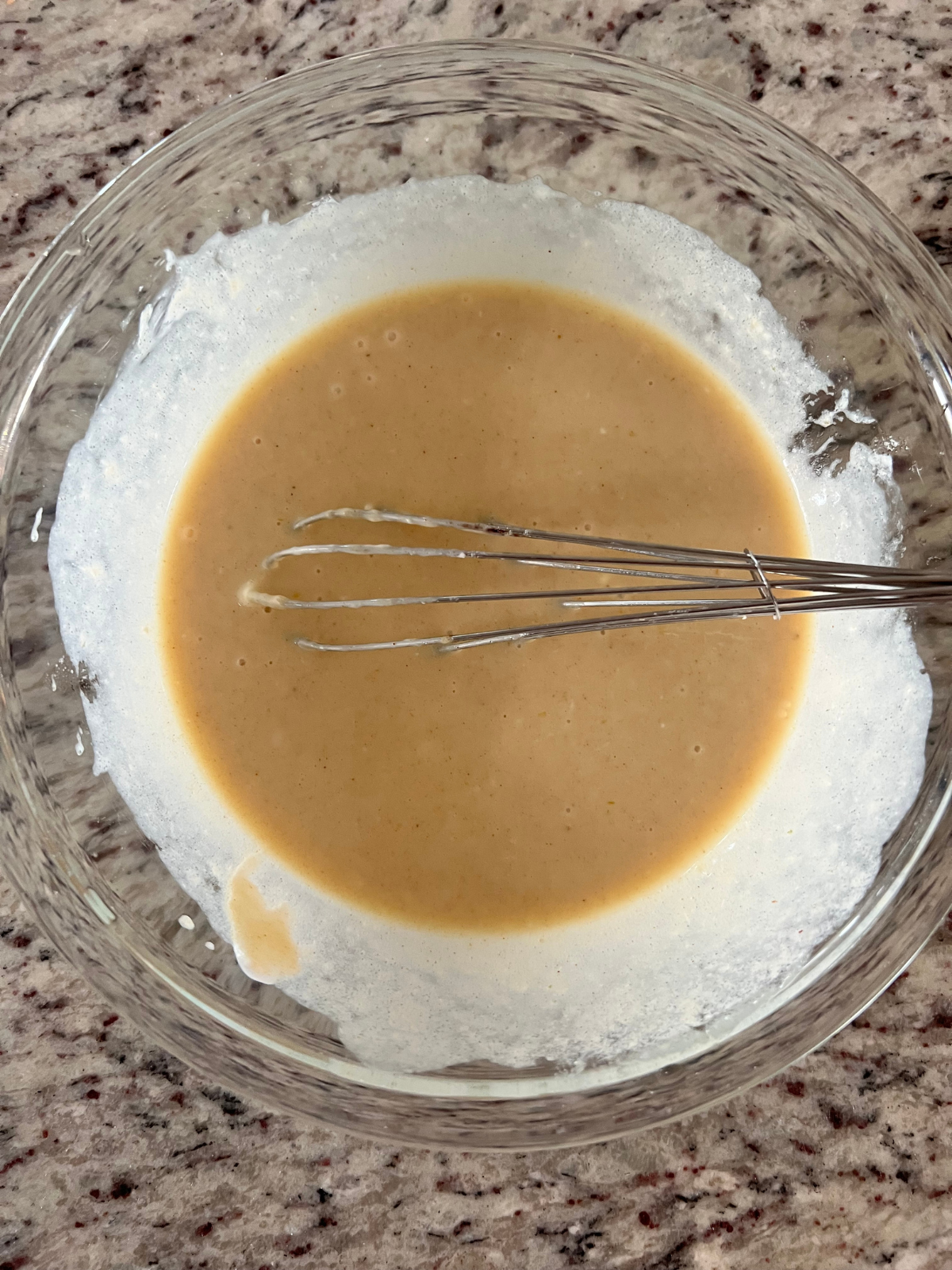 The wet ingredients for the sourdough discard apple coffee cake sit in a glass mixing bowl.