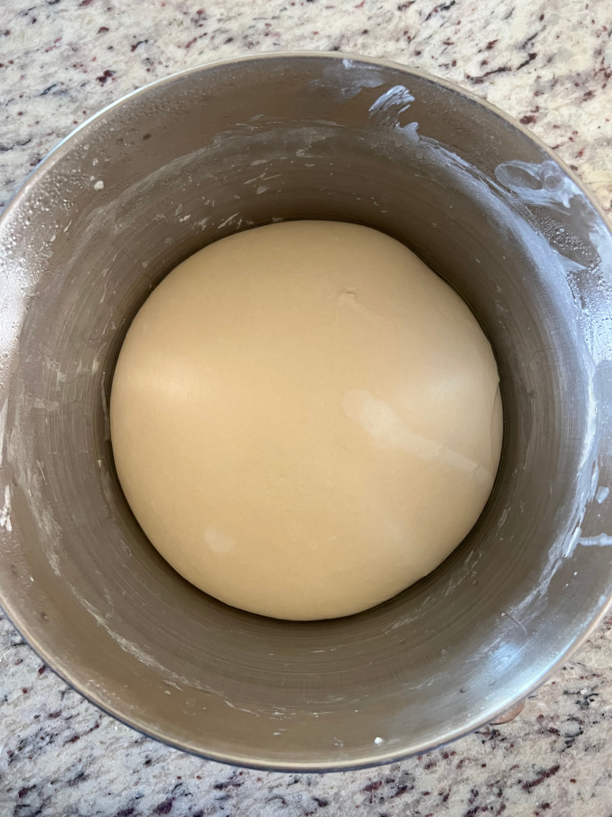 The completely bulk fermented sourdough pretzel dough is shown in the mixing bowl after an overnight ferment.