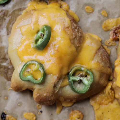 A closeup is shown of a sourdough cheddar and jalapeno soft pretzel with gooey cheese
