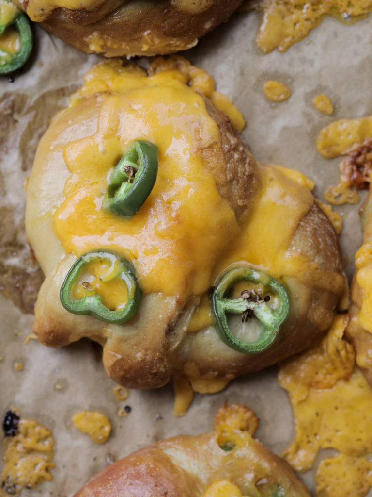 A closeup is shown of a sourdough cheddar and jalapeno soft pretzel with gooey cheese