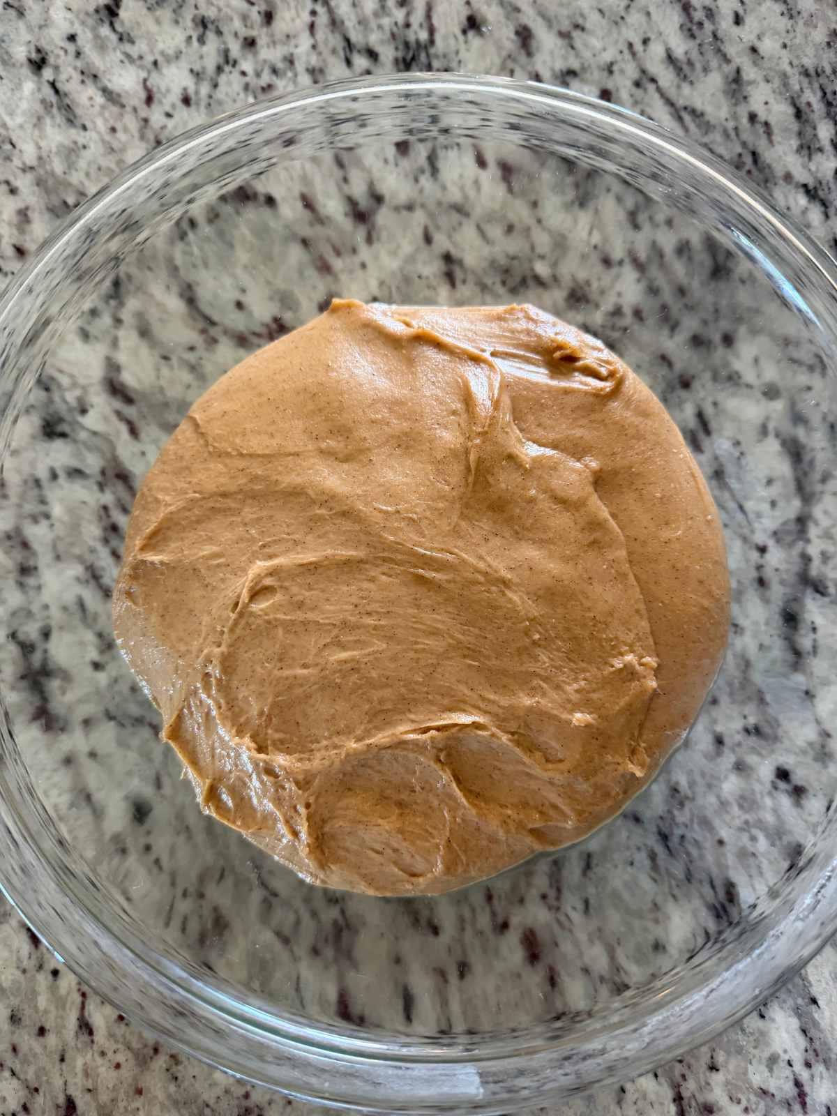 The bulk fermented sourdough pumpkin donut dough sits in a glass mixing bowl.