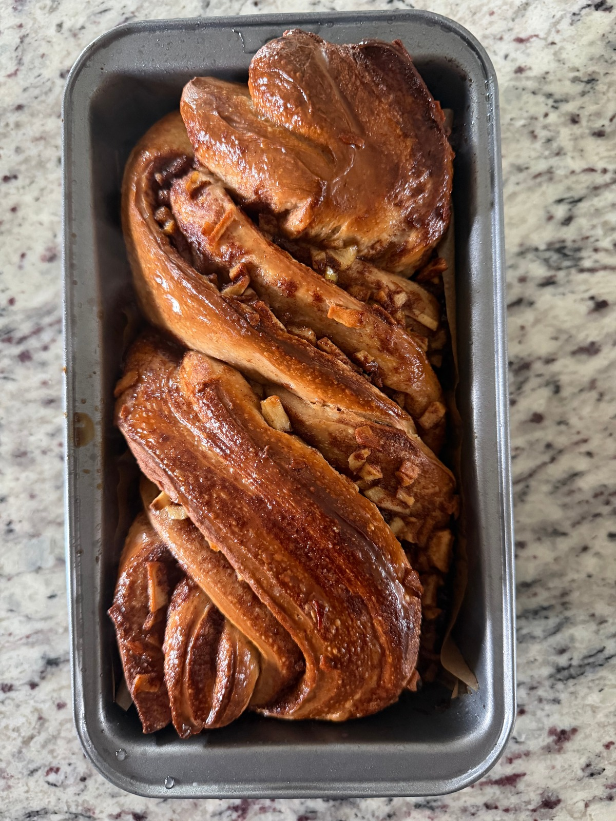 The sourdough apple-filled babka is shown in the loaf pan freshly baked.