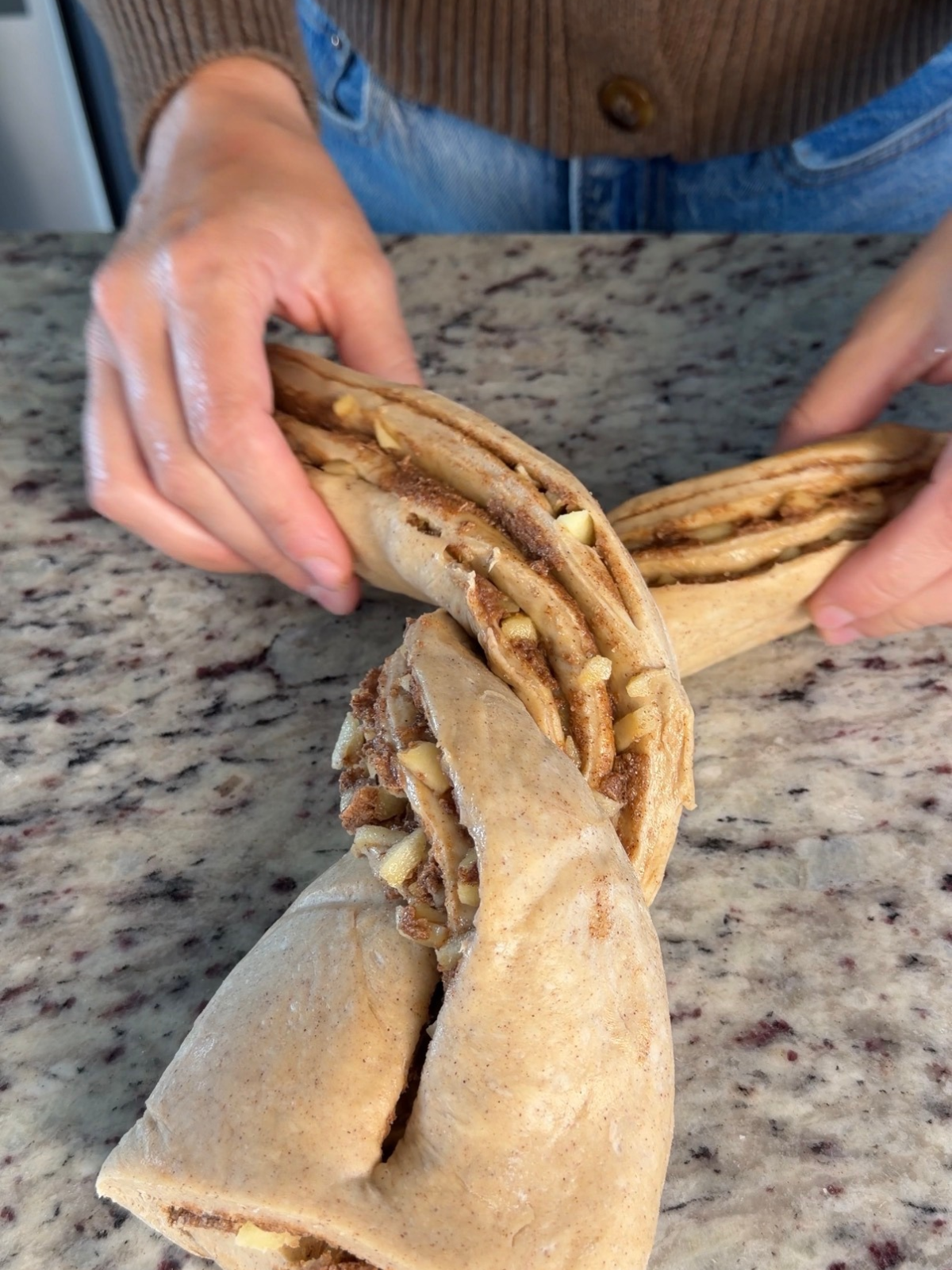 The apple babka dough is shown getting braided on the bottom of the dough.