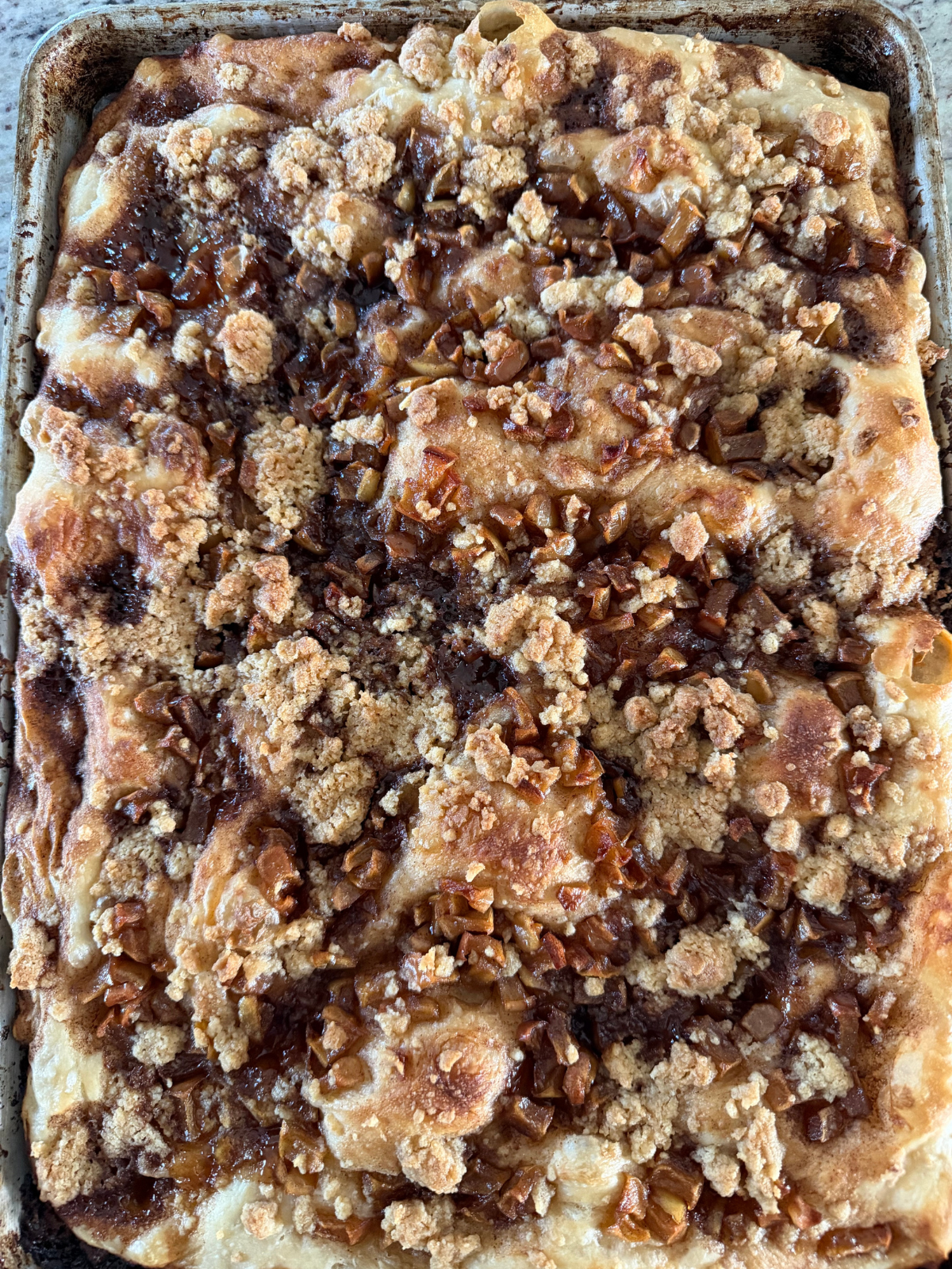 Freshly baked sourdough apple crumble focaccia is shown on the baking sheet.