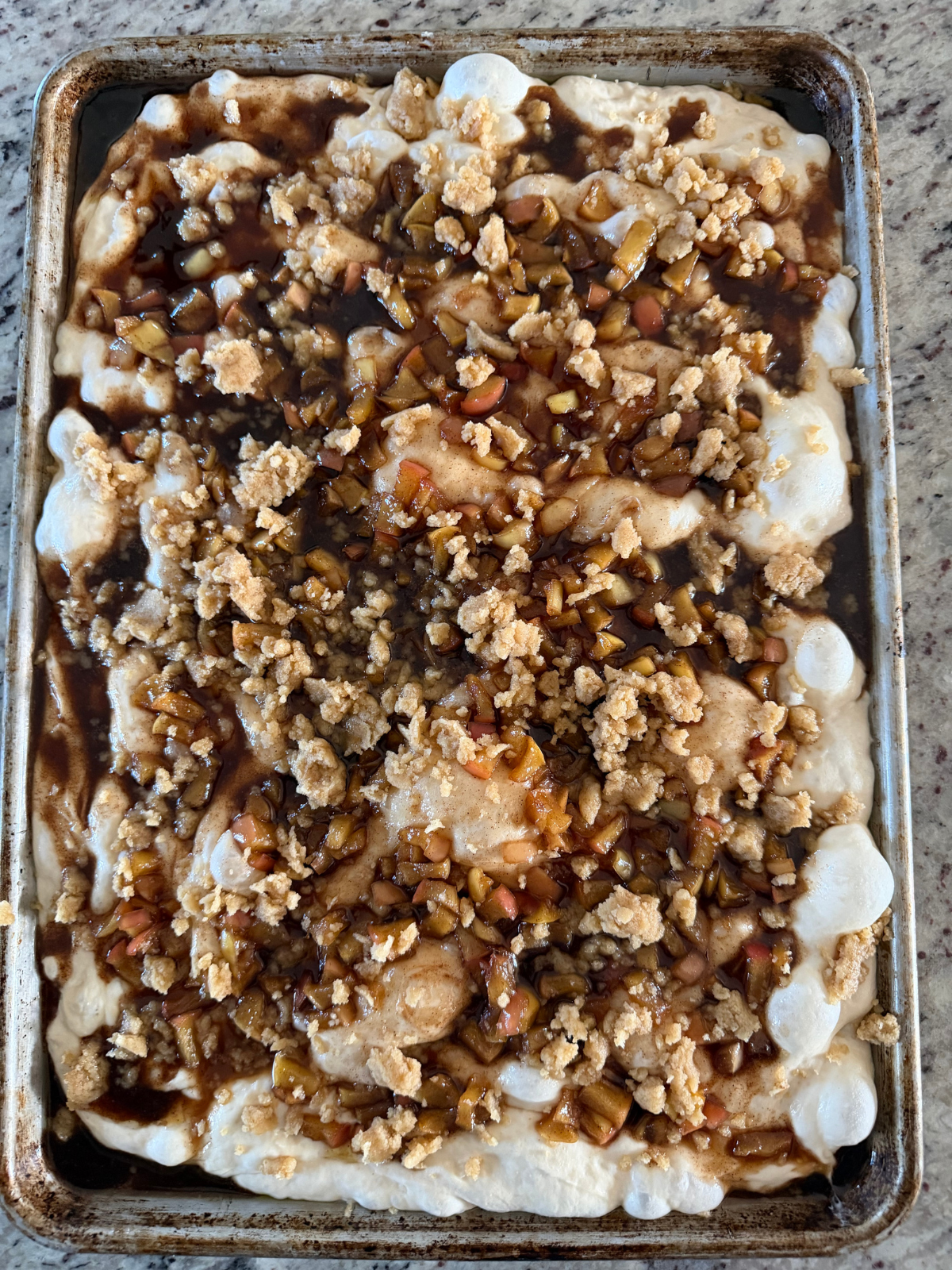 The unbaked sourdough apple struesel focaccia is shown on the baking sheet before baking.
