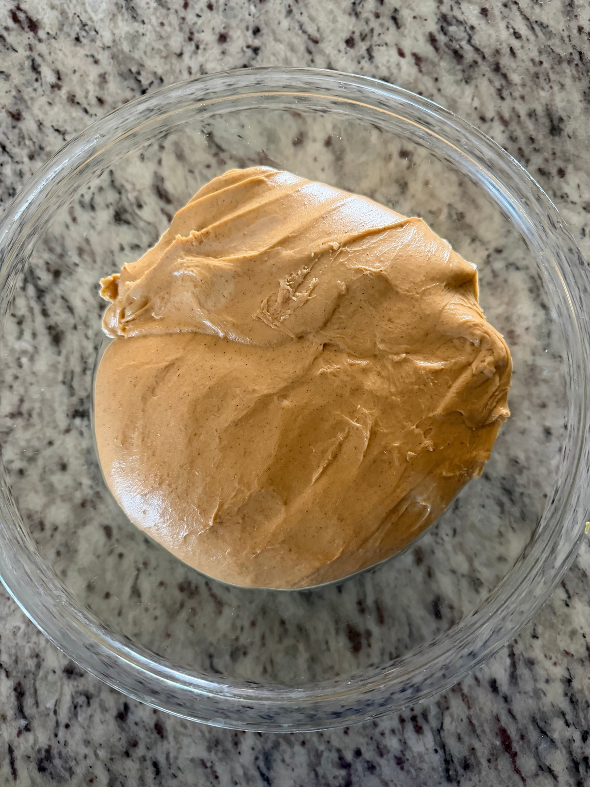 Sourdough pumpkin brioche dough sits fermenting in a glass bowl.