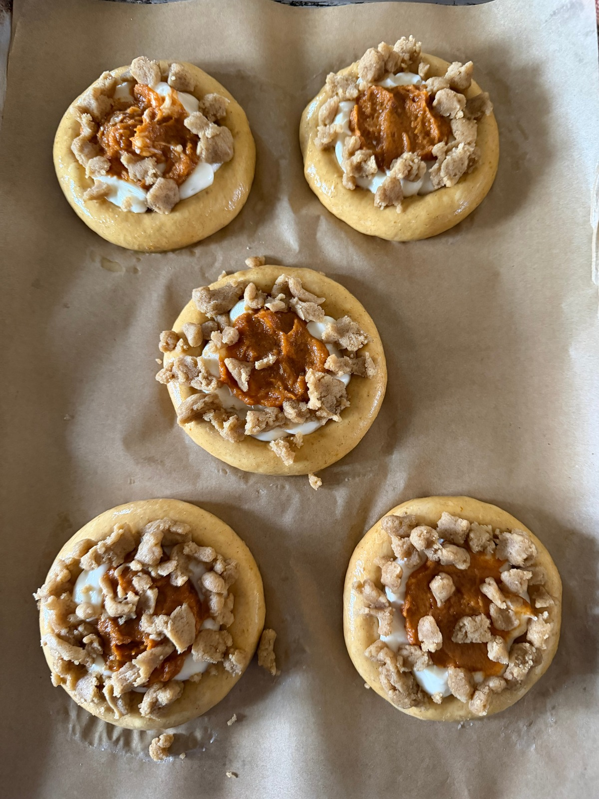 The sourdough pumpkin kolaches have been filled with cheesecake filling, pumpkin pie filing, and topped with a brown sugar crumble.