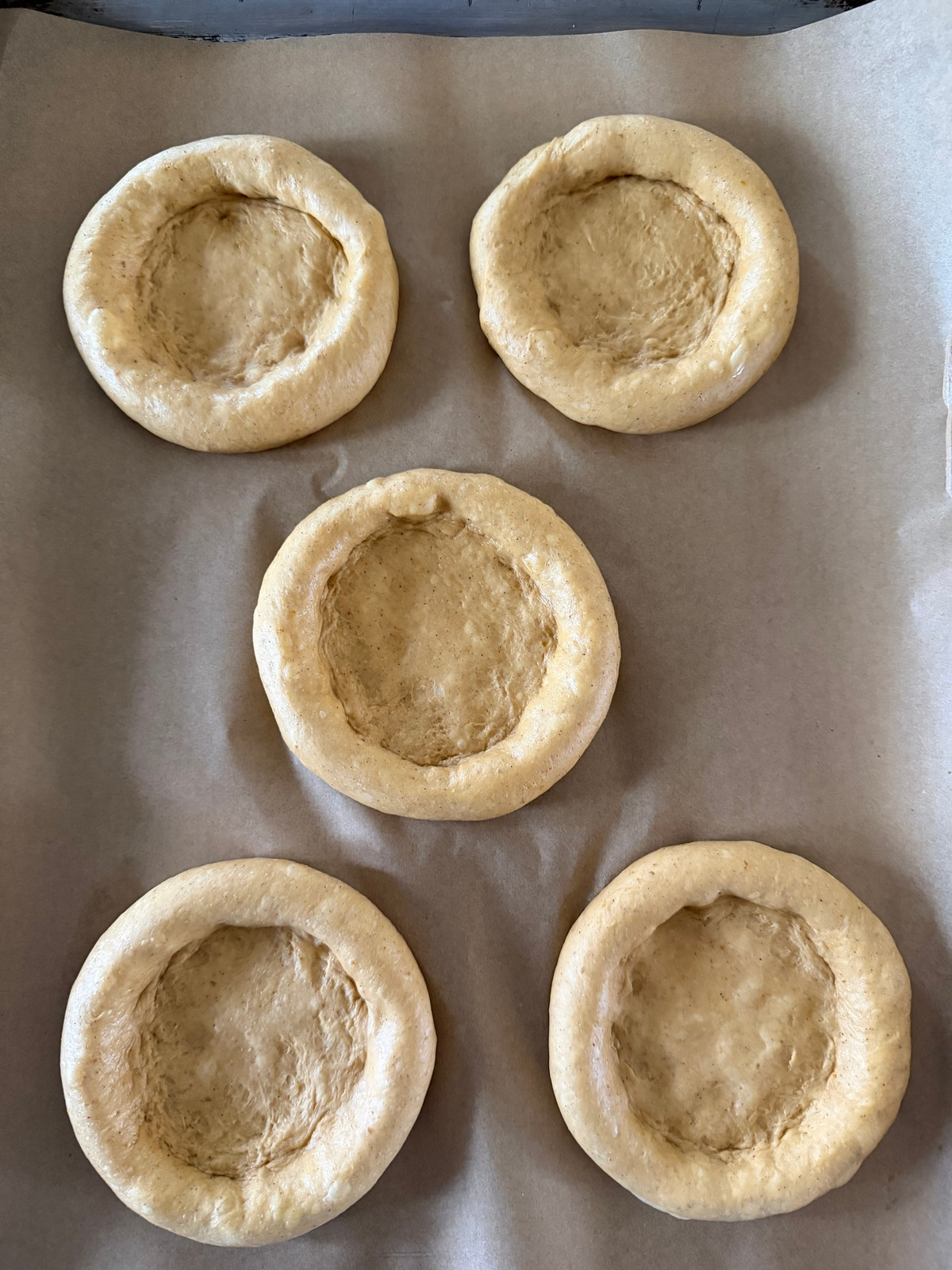 The sourdough pumpkin kolache dough balls have been shaped and rest on the baking sheet.